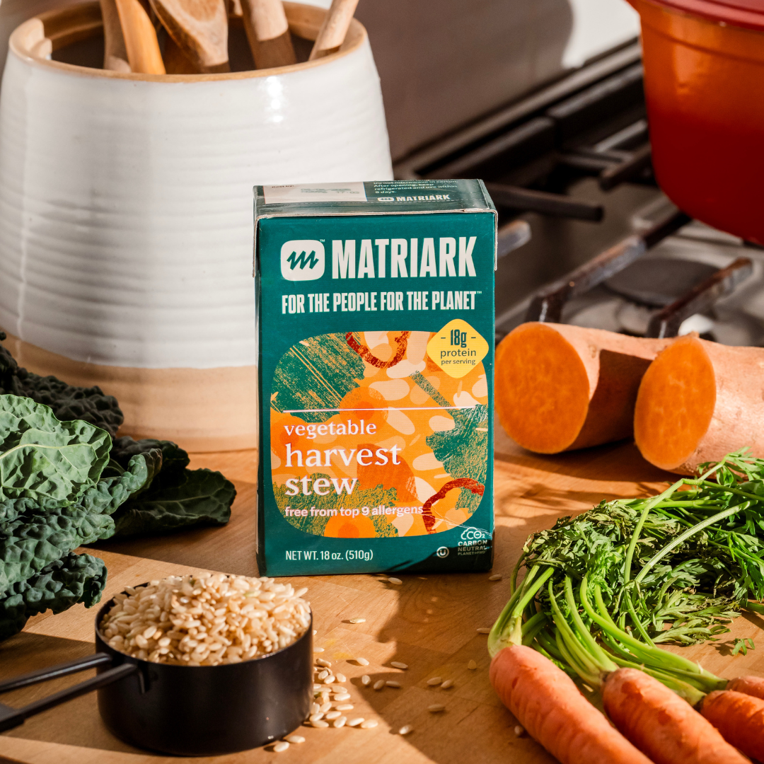 Matriark's Vegetable Harvest Stew sitting on a countertop surrounded by vegetables.