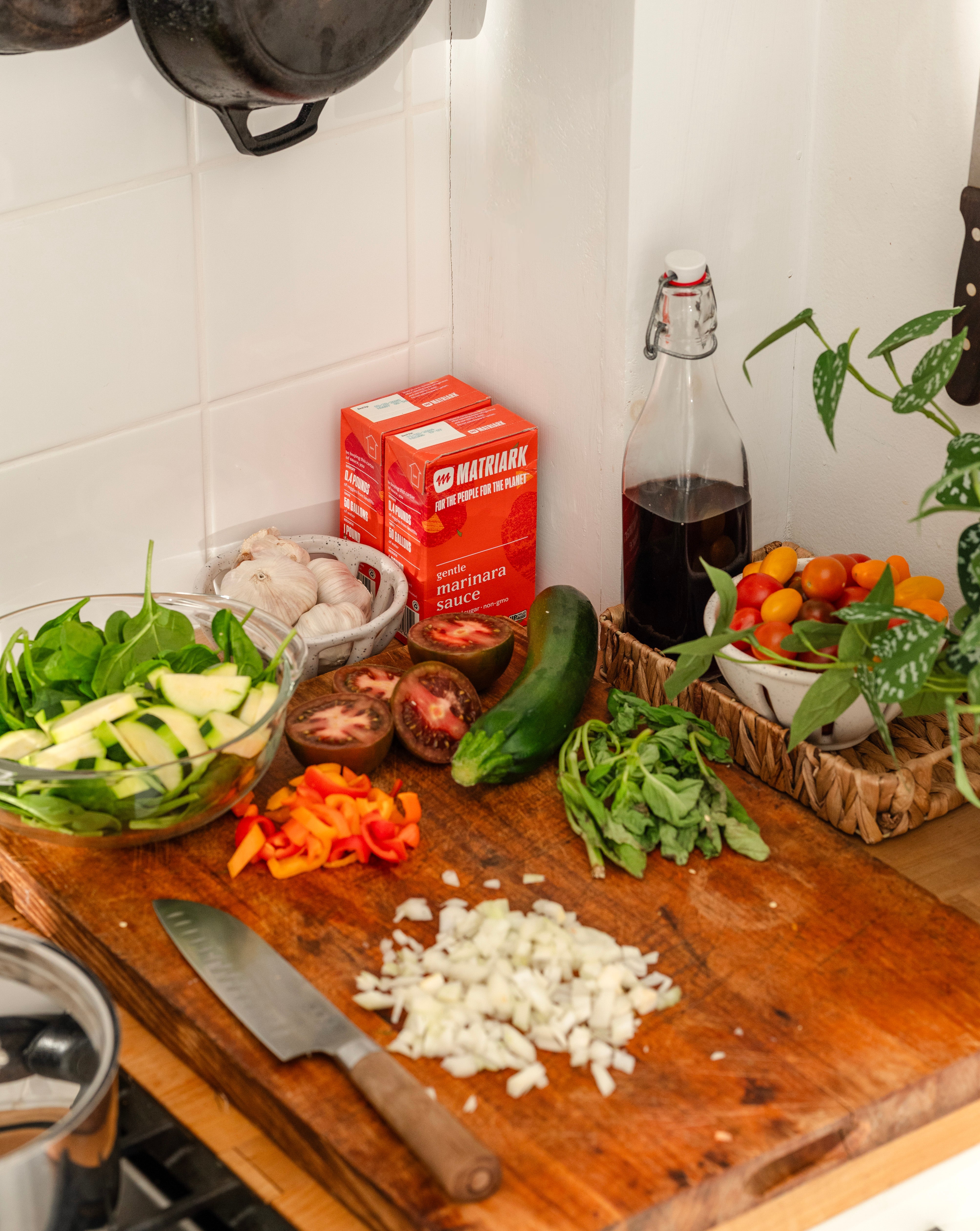 Two cartons of Matriark Gentle Marinara sit on a counter, surrounded by chopped vegetables.