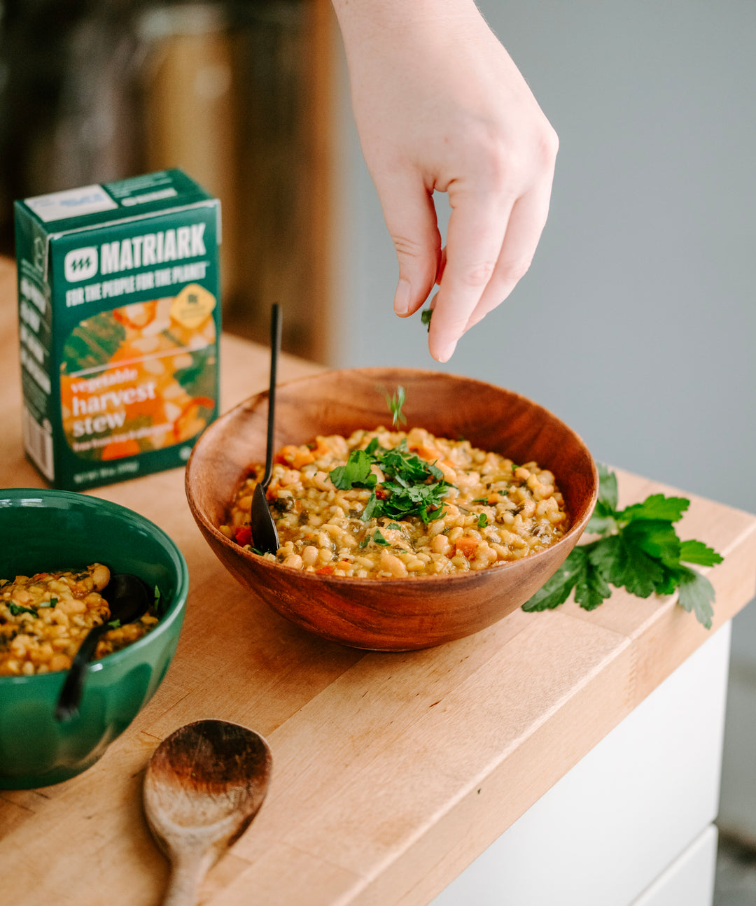 Matriark's Vegetable Harvest Stew sitting on a countertop, being garnished with parsley.